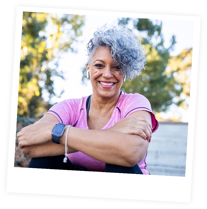 Smiling woman with curly hair outdoors.